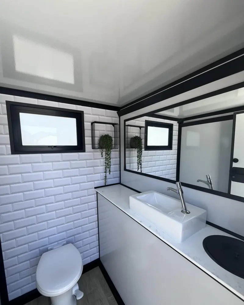 Tiled interior of a restroom trailer with vanity and toilet