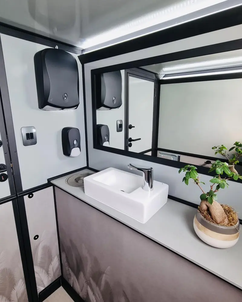 Restroom trailer vanity with sink, mirror and soap dispenser